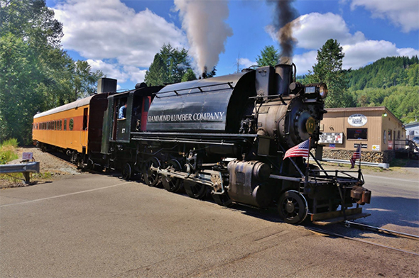 The FRA released a revised schedule of fees assessed in the case of any penalties found during FRA audits and inspections. This may impact all railroads, even small tourist carriers that operate vintage steam like the Mt. Rainier Scenic Railroad, seen here passing through a grade crossing in Elbe, Washington on the 4th of July weekend. Image © 7/2016 by Nikki Burgess; all rights reserved.